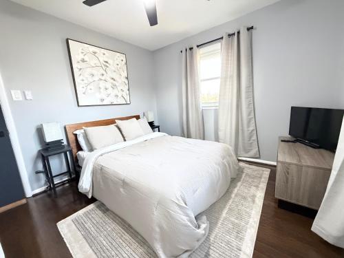 Un dormitorio blanco con una cama y un televisor. en Gambrills Modern Retreat near Annapolis & Ft Meade, en Gambrills