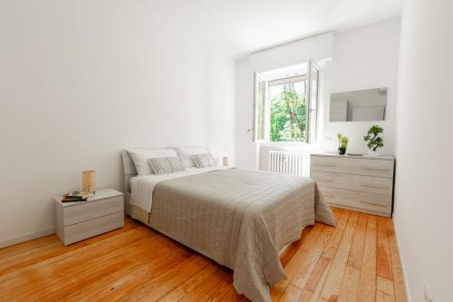Una habitación blanca con una cama y una ventana en Milan - Refuge in the Green, en Cusano Milanino