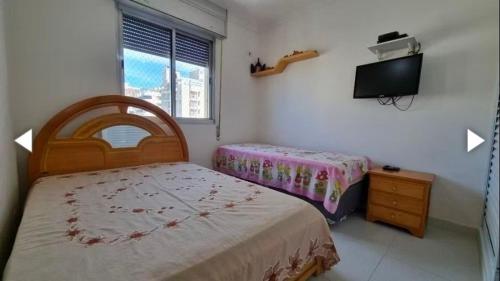 グアルジャにあるPraia de Pitangueirasのベッド2台と薄型テレビ付きのベッドルーム