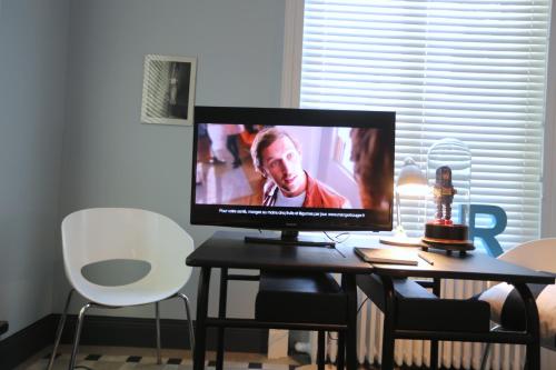 a computer monitor on a desk with two white chairs at Queen Christine in Villeneuve d'Ascq
