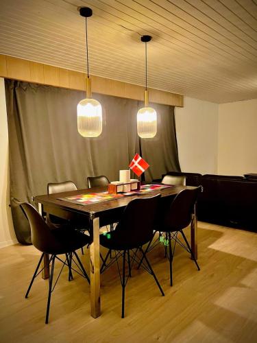 a dining room with a table with chairs and lights at Family Villa, 2 min lalandia, Beach & Ferry, free parking, Fastest Fiber Internet in Rødby