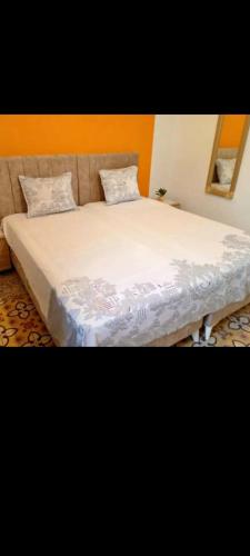 ein Bett mit weißen Laken und Kissen in einem Zimmer in der Unterkunft La coquette de sidi bousaid in Sidi Bou Saïd