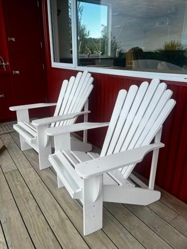 two white rocking chairs sitting on a porch at Redshed Studio Mangawhai in Mangawhai