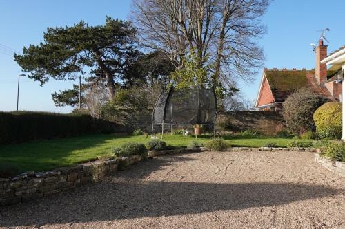 un jardín con una pared de piedra y un parque infantil en Big Group Bungalow, Sleeps 9, Perfect for Families, en Sturminster Newton