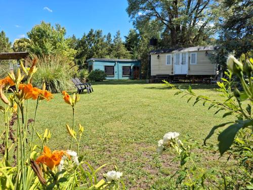 een tuin met een huis op de achtergrond met bloemen bij Las Nativas de Areco in San Antonio de Areco