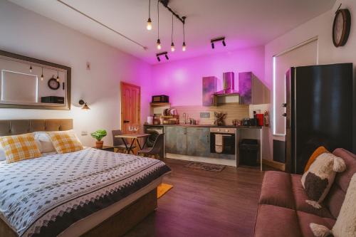 a bedroom with a bed and a kitchen with purple walls at Luxury Industrial Studio Leeds Near Brudenell social club & Headingley Stadium in Headingley