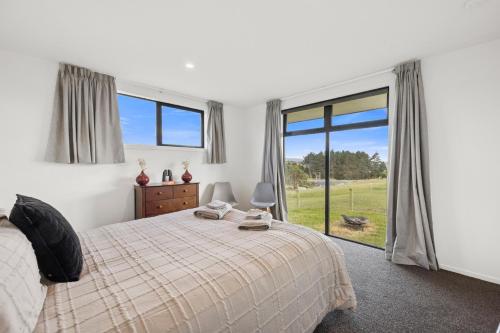 Un dormitorio con una cama y una ventana grande. en Seabreeze Lookout - Moeraki Holiday Home, en Moeraki