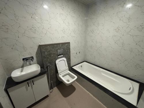 a bathroom with a sink and a toilet and a tub at Hotel Pragya Paradise in Indore