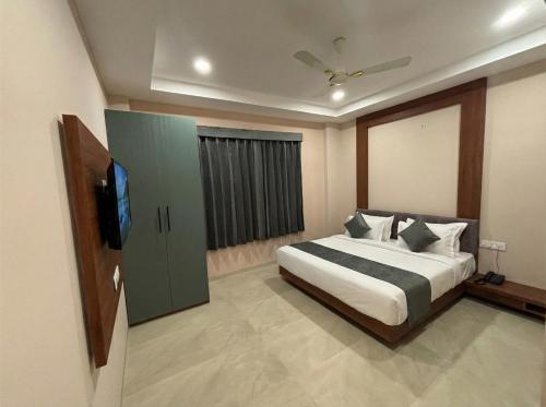 a bedroom with a bed and a flat screen tv at Hotel Pragya Paradise in Indore