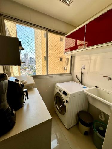 a laundry room with a washing machine and a sink at Ap inteiro St Bueno 2 quartos in Goiânia