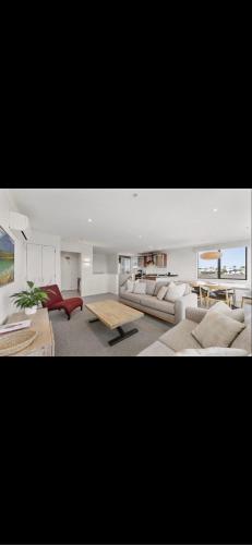 a living room with couches and a table at Cutterscove Resort Apartments in Mount Maunganui
