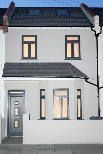 a white house with four windows and a door at Luxury Rooms Near Heathrow in Cranford