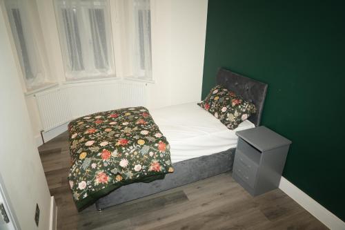 a small bed in a room with a green wall at Luxury Rooms Near Heathrow in Cranford