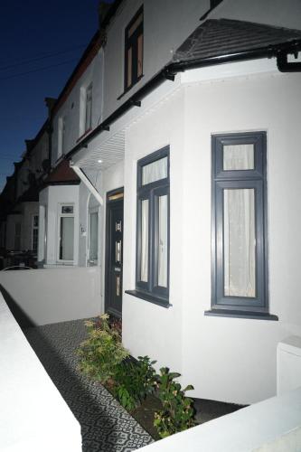 a white building with two windows and a door at Luxury Rooms Near Heathrow in Cranford