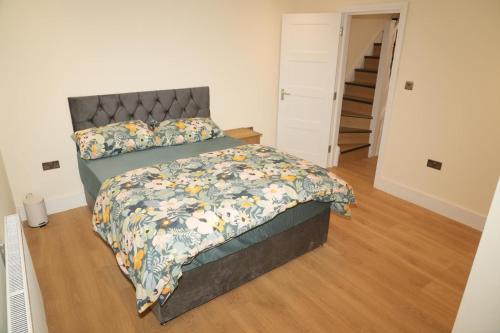 Un dormitorio con una cama grande con una colcha floral. en Luxury Rooms Near Heathrow, en Cranford