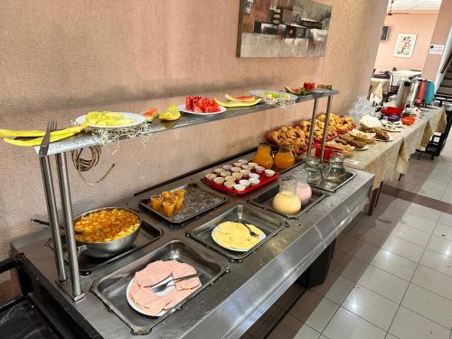 een buffet met veel verschillende soorten eten bij Hotel en villa carlos paz centrico con desayuno y pileta Nuevo Enzo in Villa Carlos Paz