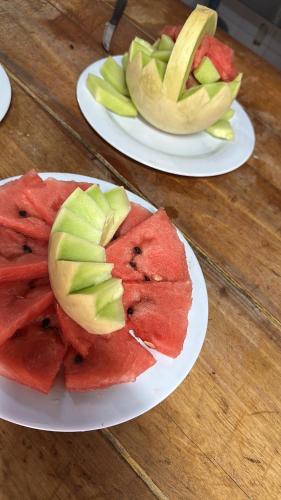 Twee schalen met watermeloen en appels op een houten tafel. bij Hotel en villa carlos paz centrico con desayuno y pileta Nuevo Enzo in Villa Carlos Paz