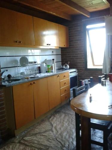 a kitchen with wooden cabinets and a table and a window at Club carilo playa Edificio del bosque in Carilo