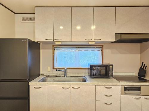 una cucina con lavello e microonde di furano lavender house a Furano