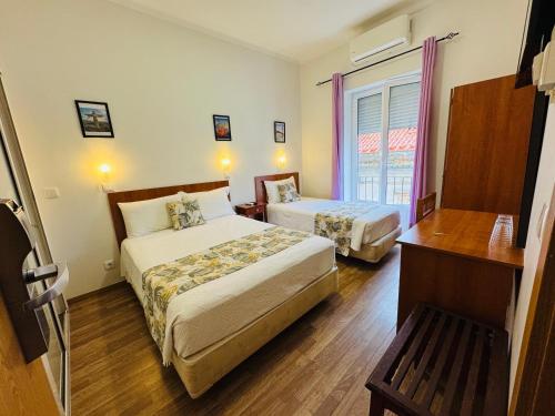 a hotel room with two beds and a window at Residencial Camoes in Lisbon