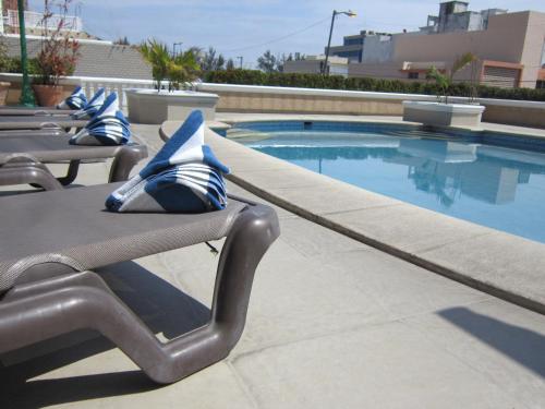 a pool with lounge chairs next to a swimming pool at Hotel Baluarte in Veracruz