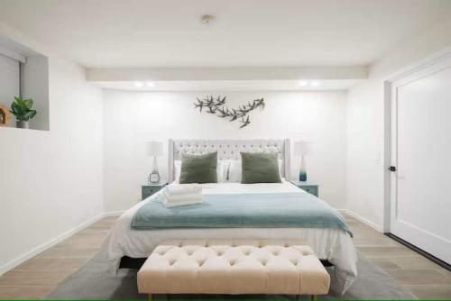a white bedroom with a large bed and a bench at Luxury 2BR Duplex 5min to Central Park in New York