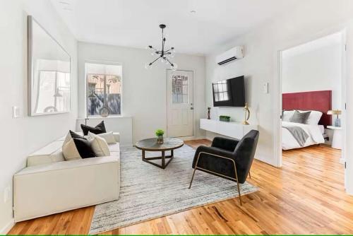 sala de estar blanca con sofá y cama en Luxury 3BR Duplex w Private Patio in Upper East, en Nueva York