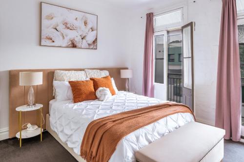 een slaapkamer met een bed met oranje kussens en een raam bij 3BR CBD Aircon Redfern family home in Sydney