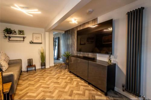 a living room with a couch and a flat screen tv at Telford Family 3 Bedroom Retreat in Oakengates