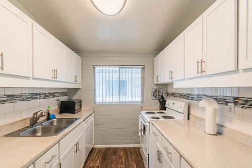 a kitchen with white cabinets and a sink and a window at Spacious 2 Bedroom, 2 Bath, Pool, Free Parking, Gym in Scottsdale