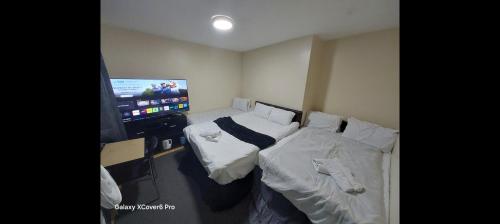a room with two beds and a flat screen tv at Romantic Guest Rooms in London