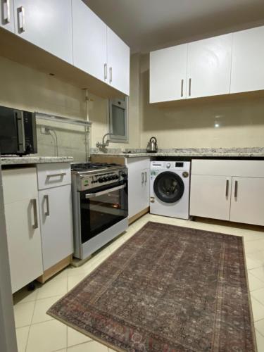 a kitchen with white cabinets and a washer and dryer at Central Park hotel apartment in Madinaty