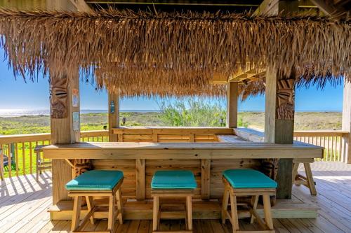 een bar op het terras van een resort met barkrukken bij Just One More Day Home in Bolivar Beach