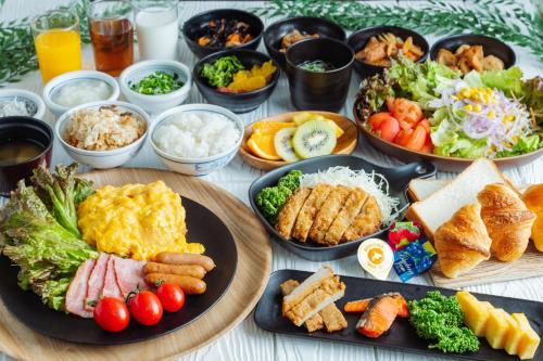 松山市にあるネストホテル松山の食べ物の皿や様々な食べ物の入ったボウルが置かれたテーブル