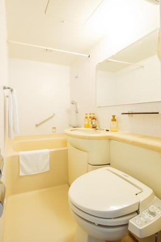 a white bathroom with a toilet and a sink at Nest Hotel Matsuyama in Matsuyama