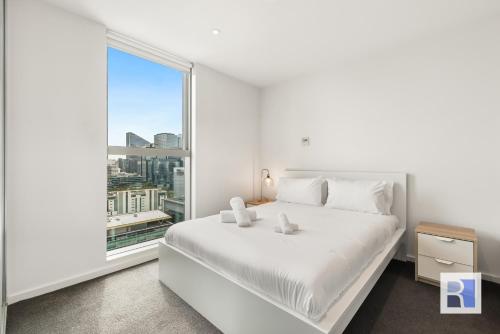 a bedroom with a white bed and a large window at REST COLLECTION Apartments on Collins Docklands in Melbourne