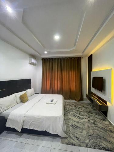 um quarto com uma cama grande e uma TV de tela plana em Carolean luxury wuye em Abuja