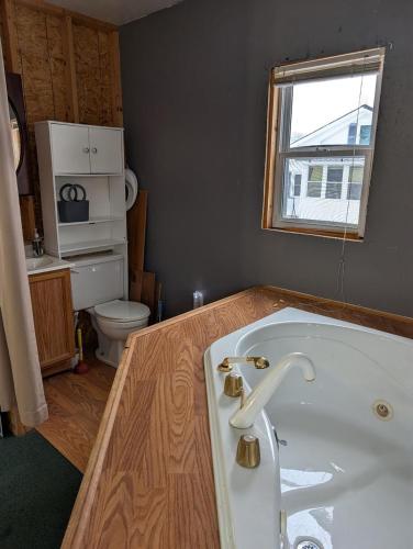 a bathroom with a white tub and a toilet at HomeAwayFromHomeMassena in Massena