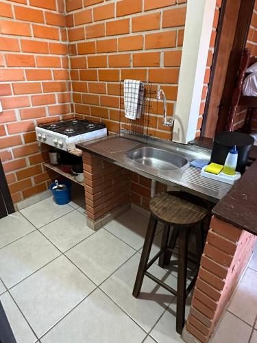 a kitchen with a sink and a brick wall at Kantinho do Mar in São Francisco do Sul
