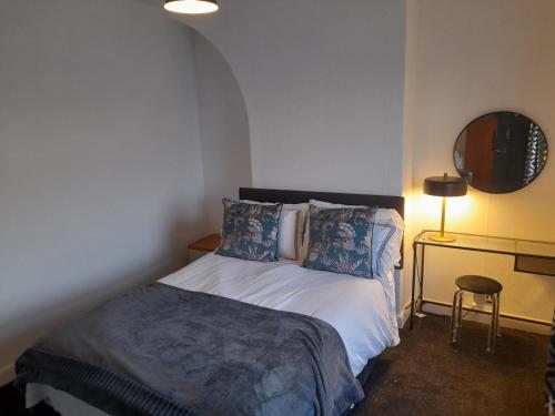een slaapkamer met een bed en een tafel met een lamp bij Terrace cottage in Blackpool
