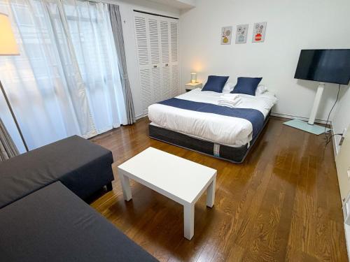 una camera da letto con un letto e un soggiorno con un divano di OUCHI HOTEL Tokaichi a Hiroshima