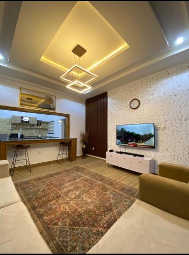 Una sala de estar con un sofá y un televisor en una pared. en Cozy home wuye, en Abuja