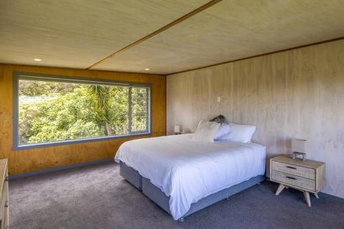 Un dormitorio con una cama grande y una ventana. en Lookout Landing by Waiheke Pure, en Waiheke Island