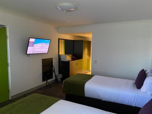 a hotel room with two beds and a flat screen tv at Mackay Oceanside Central Hotel Official in Mackay