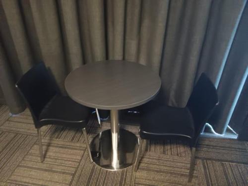 uma mesa e cadeiras num quarto com cortinas em Mackay Oceanside Central Hotel Official em Mackay