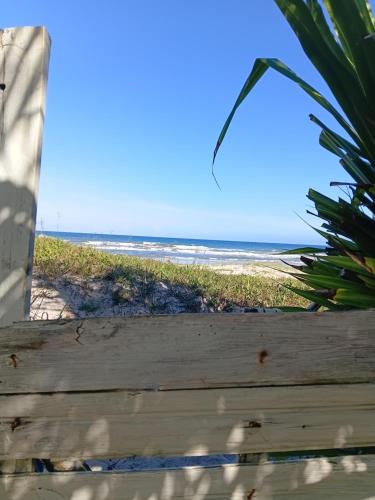 una vista sulla spiaggia da una recinzione in legno di Chalé pé na areia e vista Mar a Ilhéus