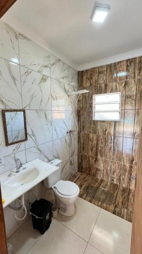 a bathroom with a toilet and a sink at Recanto Maria de Souza in Caçapava