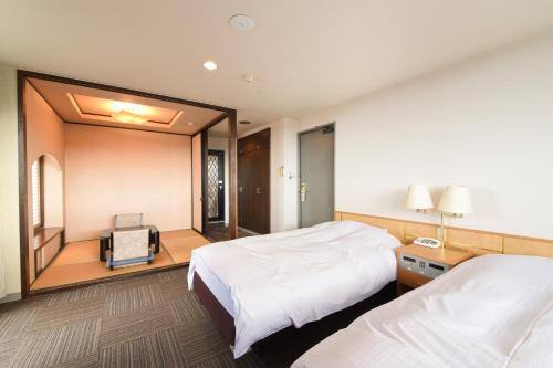 ein Hotelzimmer mit zwei Betten und einem Spiegel in der Unterkunft サンシティーホテル山代 in Kaga