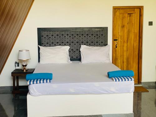 um quarto com uma grande cama branca e uma cabeceira em madeira em The Banana Cottage em Udawalawe