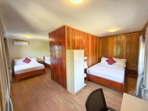 Una pequeña habitación con dos camas y una silla. en Sun & Roots Kampot Lodge, en Kampot